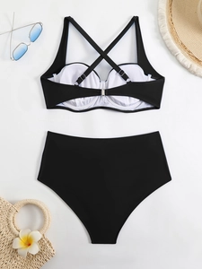 Flat lay of black high-waisted bikini with cross-back metal buckle and beach accessories