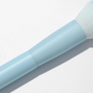 Close-up of soft white bristles and matte pastel blue handle of the makeup brush