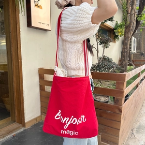 Detail of red canvas tote bag with Bonjour magic print and striped shoulder strap
