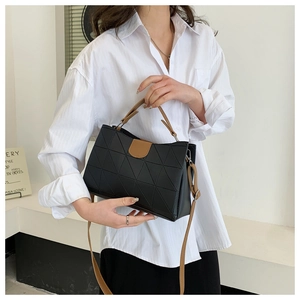 Detail of black bucket bag with geometric triangle embossing and brown leather handles
