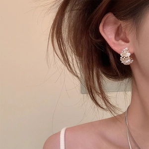 Detailed close-up of floral pearl stud earrings with resin petals and gold center