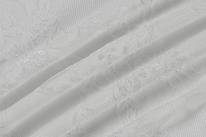 Detailed macro view of white floral lace fabric with intricate mesh texture for dress
