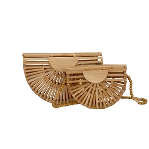 Natural woven bamboo handbag with fan-shaped design and wooden bead strap on white background