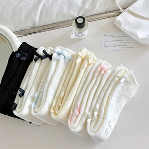 Détail de jambières en maille avec des nœuds en ruban dans divers tons pastels