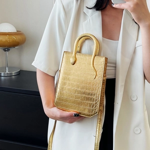Golden crocodile embossed handbag with snake handle on a minimalist white blazer model