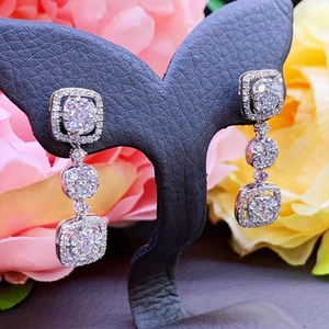 Macro detail of silver geometric drop earrings with sparkling pavé crystals on a display