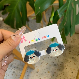 Detail of cute acrylic dog-shaped earrings held by hand on a decorative card
