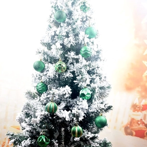Detailed view of green Christmas ornaments with varied textures on a snowy tree branch