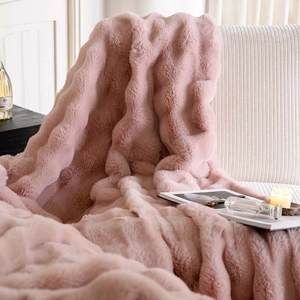 Pink faux rabbit fur throw blanket draped over a sofa in a cozy home setting