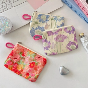 Detailed view of floral canvas storage pouches with zippers and pink lanyards on a desk