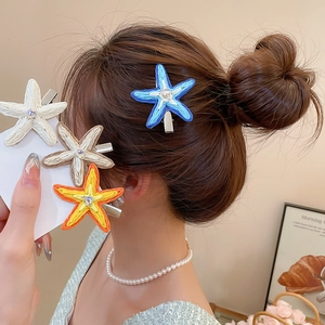 Détail de pinces à cheveux étoile de mer en raphia tressé avec strass brillant