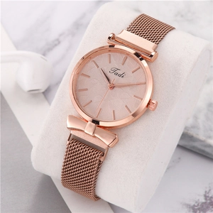 Rose gold watch with mesh strap and bow detail on a marble background