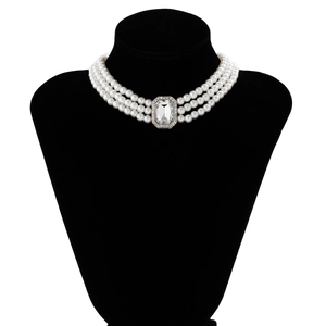 Close-up of triple-layered pearl necklace with a radiant crystal pendant on a neck display