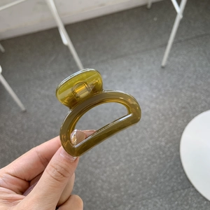 Detail of a dark green translucent hair claw clip with a strong metal spring mechanism