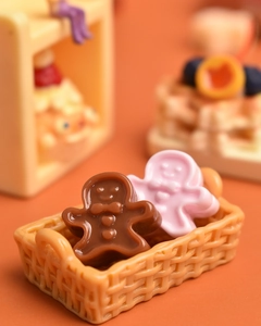 Miniature resin gingerbread figures in a tiny beige woven basket for dollhouse decor