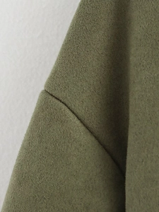 Detailed close-up of double stitching and suede texture on army green jacket shoulder