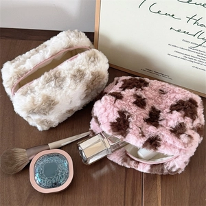Macro view of plush leopard print makeup bags with perfumes on a wooden table