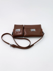 Detail of dual-compartment baguette bag in brown leather with silver twist-lock hardware