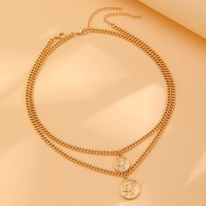 Gros plan d'un collier doré double épaisseur avec pendentifs pièces et maille gourmette
