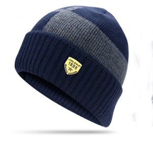 Close-up of a blue and gray knitted winter hat featuring a yellow shield logo patch