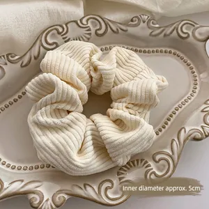 Creamy white plush scrunchie with 5cm inner diameter on elegant ceramic tray