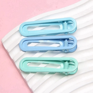 Three shades of blue 6cm U-shaped hair clips displayed on a white wavy board