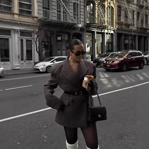 Women's oversized double-breasted grey blazer with a thin leather belt in urban street setting