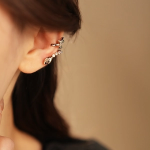 Detailed close-up of a silver snake-shaped ear cuff with sparkling zircon on model ear