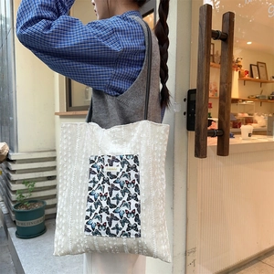 Close-up of pleated canvas tote bag with colorful butterfly patch and black strap