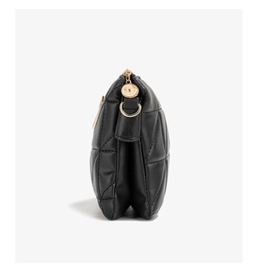 Side view of black quilted crossbody bag showing gold zipper and hardware details