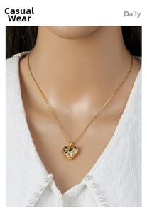 Detail of a gold heart pendant necklace inlaid with multi-color gemstones on a model