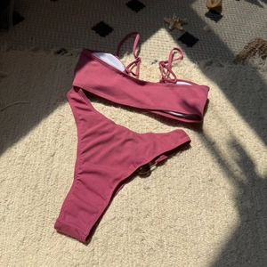 Detailed flat lay of ribbed pink bikini with seashell beach decor and tortoiseshell rings