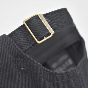Detail of adjustable metal buckle and black cotton strap on the back of baseball cap