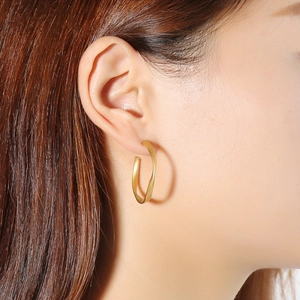 Close-up of minimalist twisted stainless steel gold hoop earrings on a female model