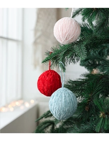 Detail of soft chenille knitted Christmas balls in pink and red hanging on a tree