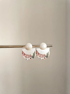 Détail de boucles d'oreilles ethniques en bois avec imprimé désert et métal brossé poli