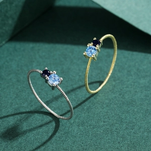 Minimalist S925 silver twist rings in gold and silver with blue stones on green background