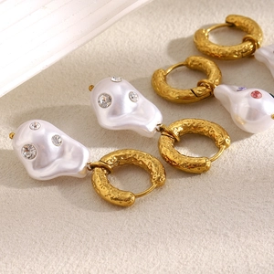 Detail of gold baroque pearl earrings with colorful gemstones and hammered texture