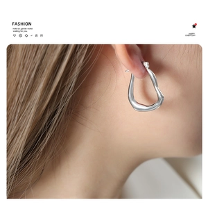 Close-up of a silver geometric titanium earring worn by a model for a modern look