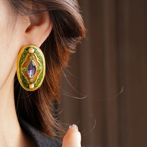 Close-up of vintage flower earrings with purple stone and pearls on a model's ear
