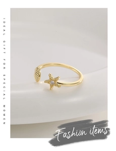 Nahaufnahme eines goldenen Seestern- und Muschelrings mit Zirkonia auf weißem Grund