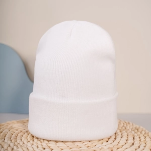 Gros plan d'un bonnet en tricot blanc montrant des côtes fines et un large revers épais