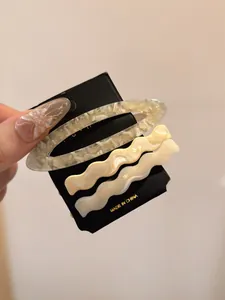 Detailed view of three minimalist acetate hair clips in cream white and marble textures