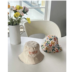 Detailed close-up of beige cotton bucket hat with CUTE embroidery and colorful floral print