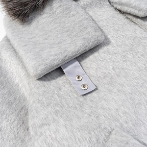 Détail d'un manteau en laine gris avec col en fausse fourrure et fermeture éclair en métal