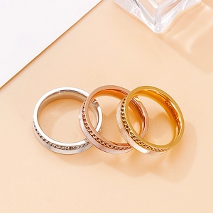Detail of three-tier stackable rings featuring central chain link textures in three metal tones