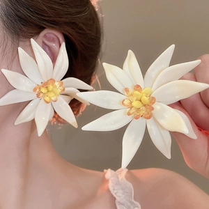 Detailed view of oversized white resin flower earrings with colorful beaded centers