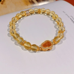 Vue macro d'un bracelet en perles citrines avec un pendentif cœur doré et zircons