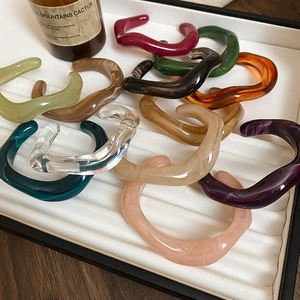 Close-up of irregular resin bangles with marble texture in various colors on a tray