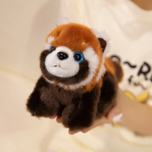 Cute red panda plush toy with sparkly blue eyes and soft brown fur held in hand